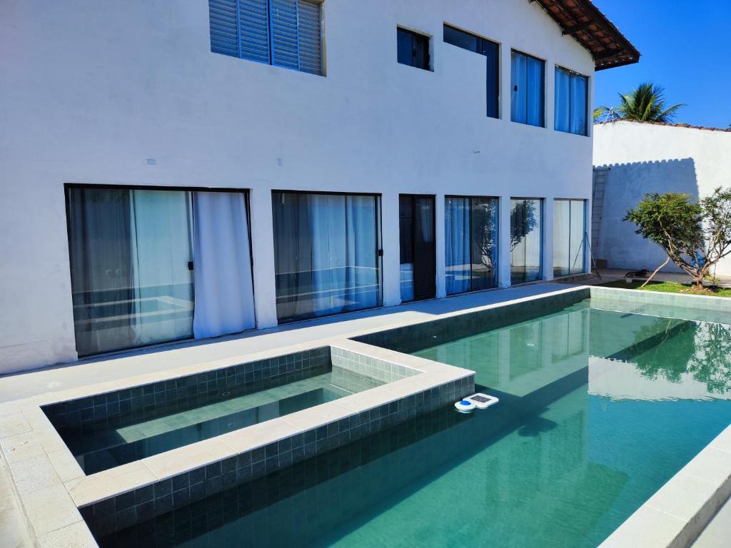 a house with a swimming pool in front of a house at 11suites casa Suite#1 in Caraguatatuba