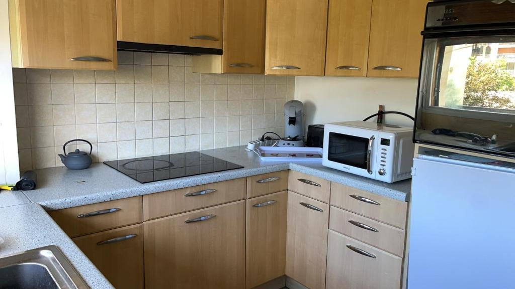 - une cuisine avec des placards en bois et un four micro-ondes blanc dans l'établissement cosy quiet, à Rueil-Malmaison