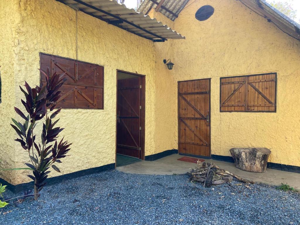 a yellow building with two doors and a plant at Chalé Único in Alto Paraíso de Goiás