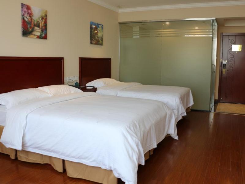2 bedden in een hotelkamer met witte lakens bij GreenTree Inn Jiangsu Suzhou Xiangcheng Huoli Island Business Hotel in Suzhou