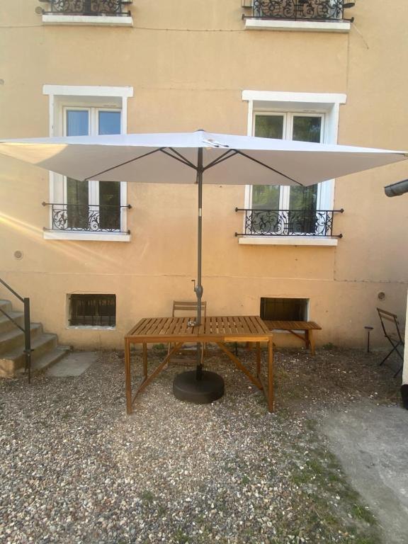 une table avec un parasol devant un bâtiment dans l'établissement Chambres rénovées proches de Paris Centre, des sites olympiques, avec belle terrasse calme, à Argenteuil