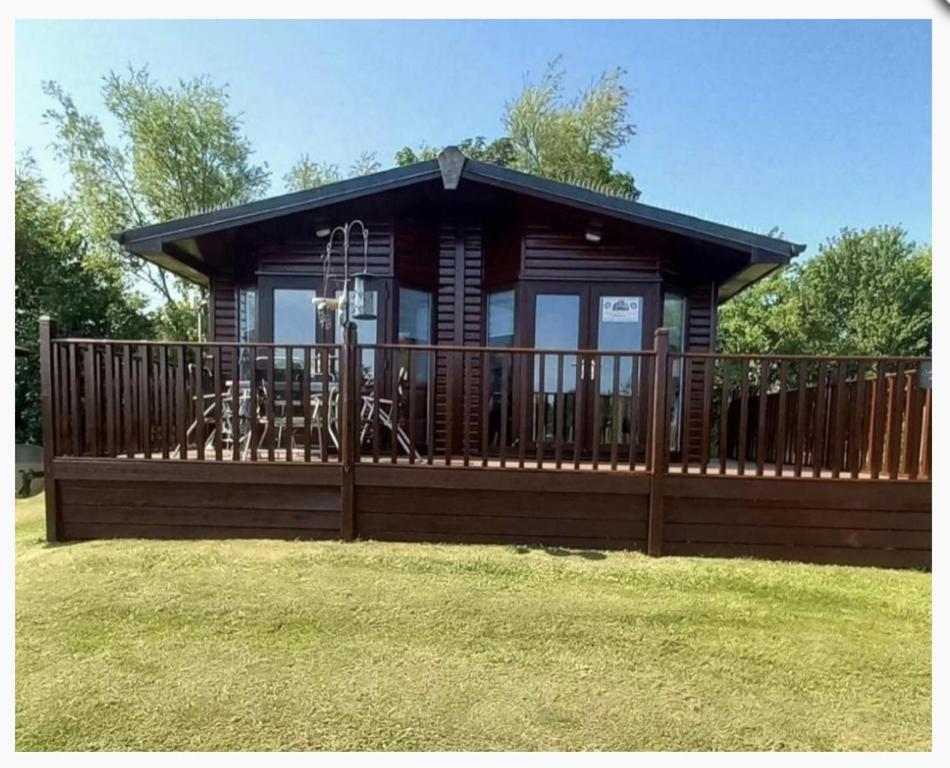 a cabin with a large deck with a fence at Lodge Retreat 8 - Haggerston Castle in Berwick-Upon-Tweed