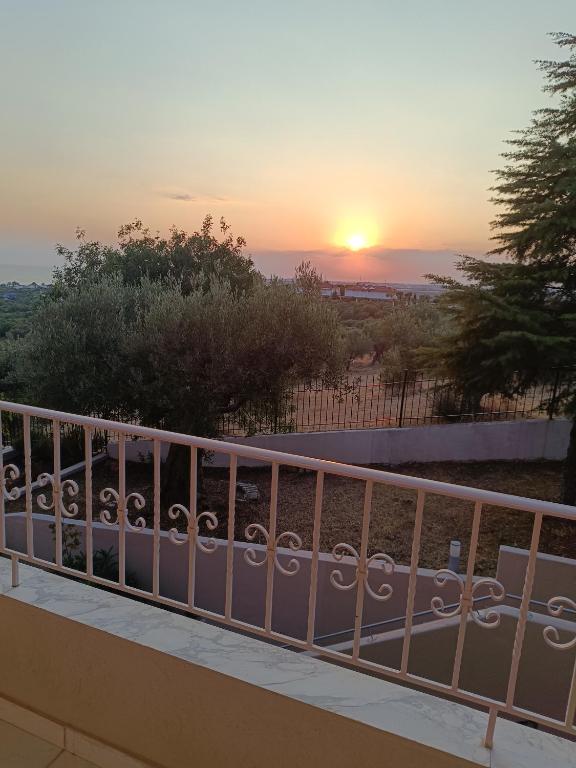 a sunset seen from a balcony with a fence at Olive & Garden in Nea Moudania
