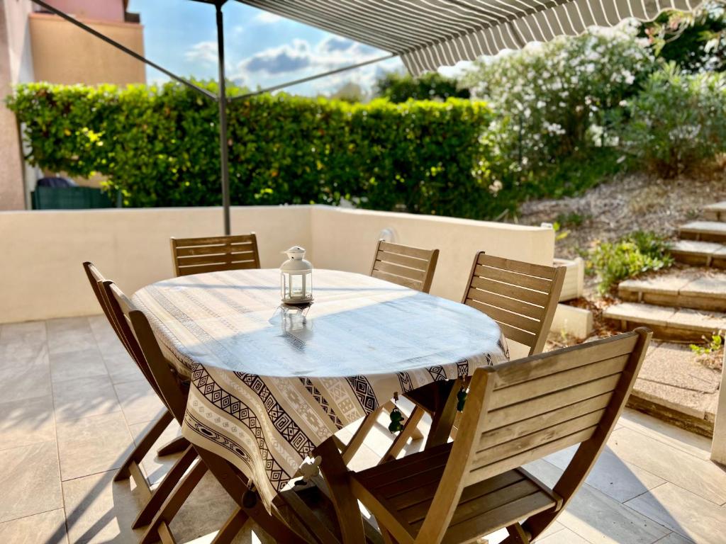 une table avec des chaises et un parasol sur une terrasse dans l'établissement Bel appartement avec terrasse, au Cap d'Agde