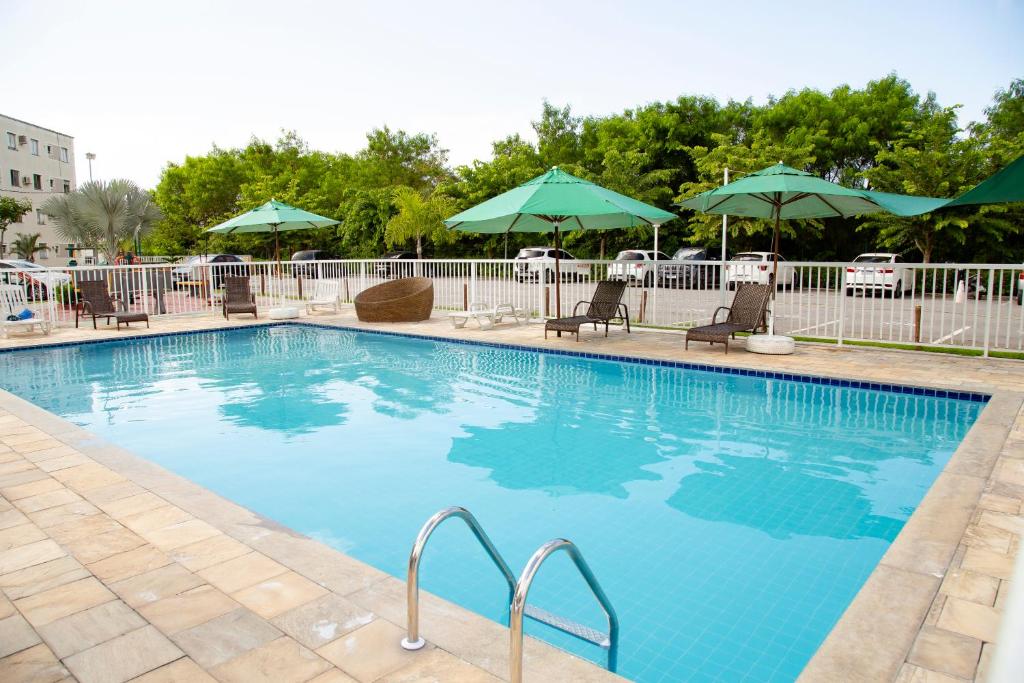 een groot zwembad met stoelen en parasols bij Conforto & tranquilidade in Rio das Ostras