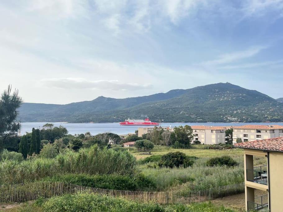 un grand navire rouge sur l'eau avec des montagnes dans l'établissement Appartement résidence Bel Orizonte Propriano, à Propriano