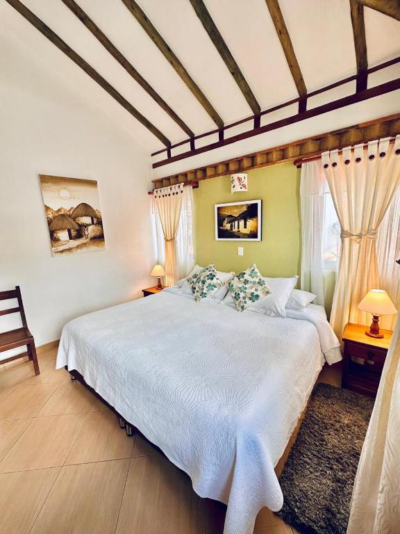 a bedroom with a large bed with white sheets at Hotel Villa del Angel in Villa de Leyva