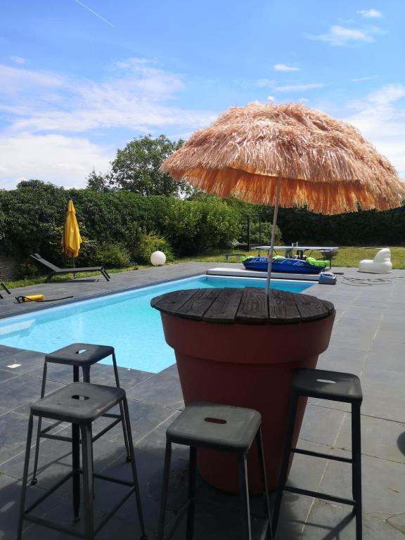 un parasol et deux tabourets à côté d'une piscine dans l'établissement Le Nid - Route des impressionnistes & Giverny, à Saint-Martin-la-Garenne