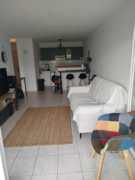 un salon avec un canapé blanc et une cuisine dans l'établissement L'appartement de Juju, à Bayonne