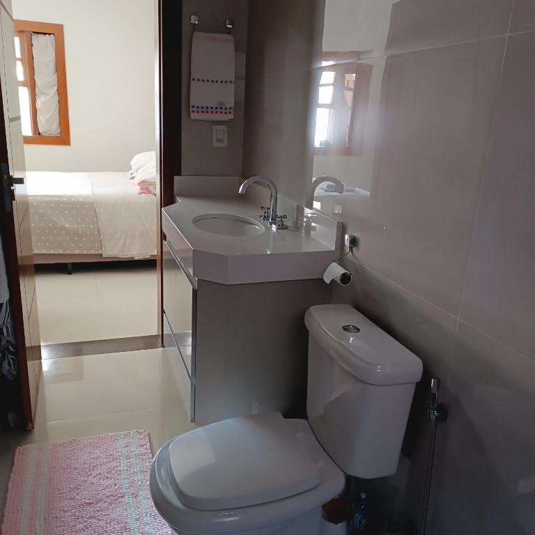 a bathroom with a toilet and a sink and a bed at Sua casa em nossa casa in Diamantina