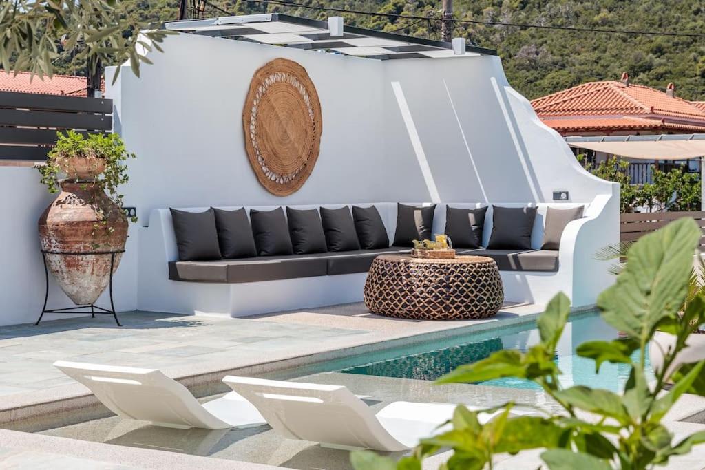 a patio with a couch and chairs next to a pool at Terpsis Origin Villa in Stafylos