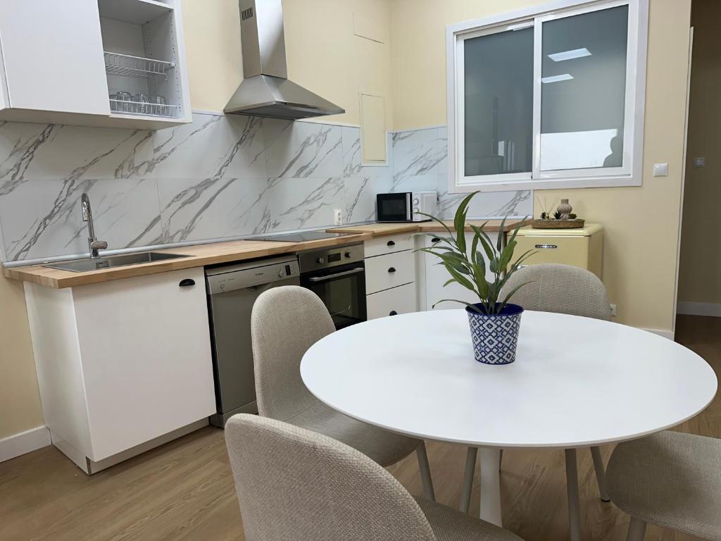 a white kitchen with a white table and chairs at Playa América-Sal y Arena in Nigrán