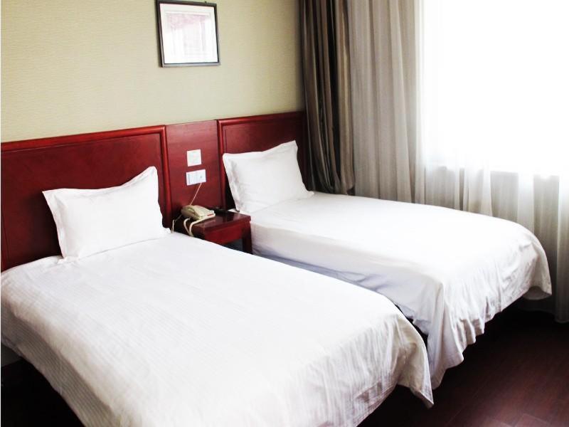 two beds in a hotel room with white sheets at GreenTree Alliance Zhejiang Zhoushan Haitian Avenue West Donghai Road Hotel in Zhoushan