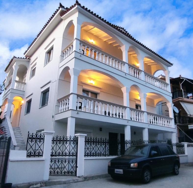 Medusa Myrina Luxury Apartments 1st Floor في ميرينا: بيت أبيض مع سيارة متوقفة أمامه