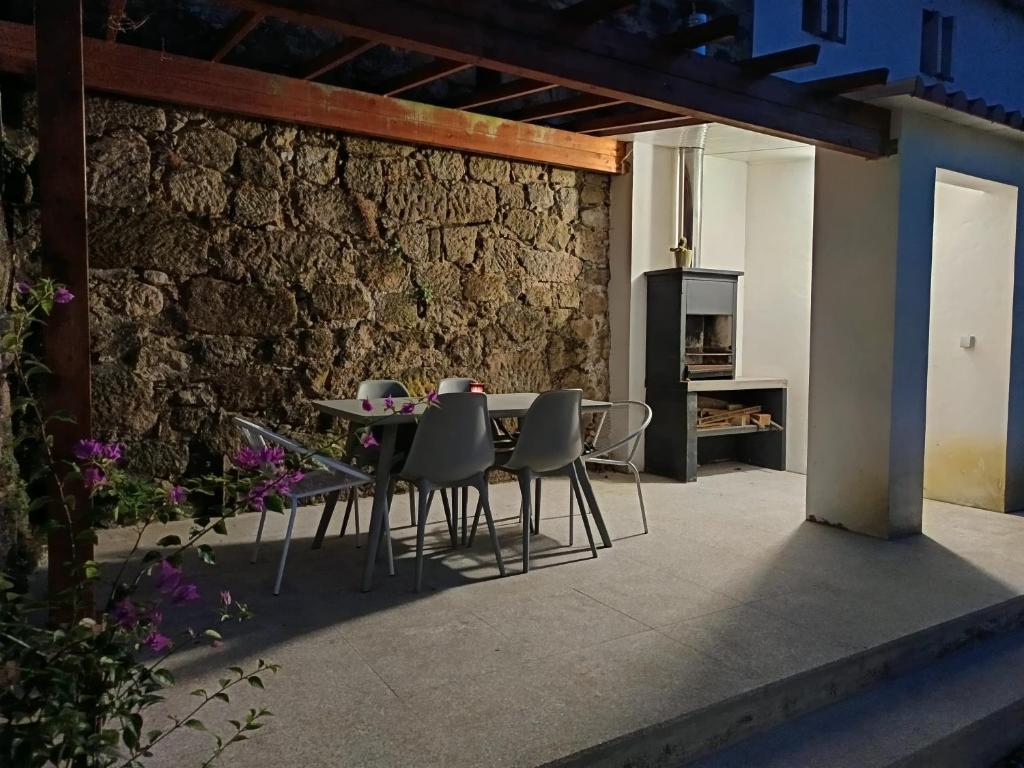 a patio with a table and chairs next to a brick wall at Casa Além Da Ponte in Vouzela