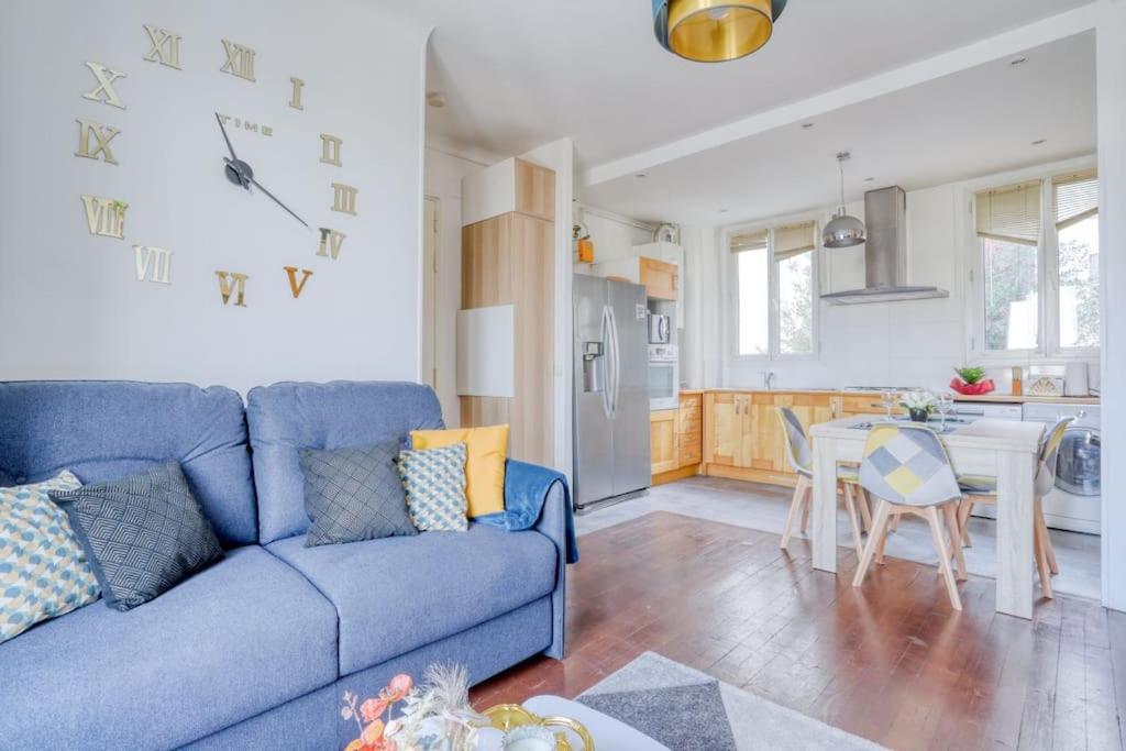 a living room with a blue couch and a kitchen at Superbe T3 très proche Gare Sartrouville in Sartrouville