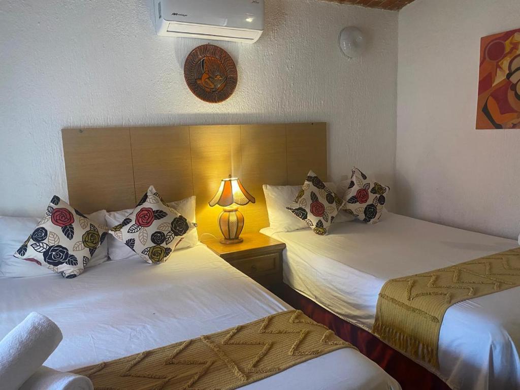 a hotel room with two beds with a lamp on it at Hotel Villas Ajijic, Ajijic Chapala Jalisco in Ajijic