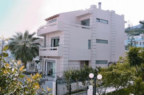 a white building with a palm tree in front of it at Maria Apartments in Agia Pelagia