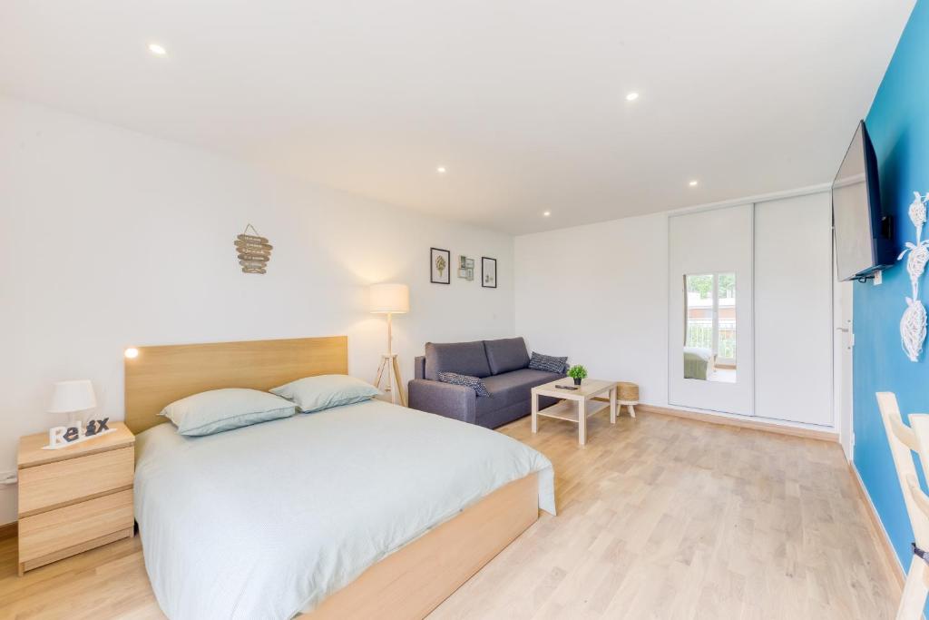 une chambre avec un grand lit et une chaise bleue dans l'établissement Appartement Entier Proche la Défense & Paris & Hôpital de Colombes - Parking privé, à Colombes