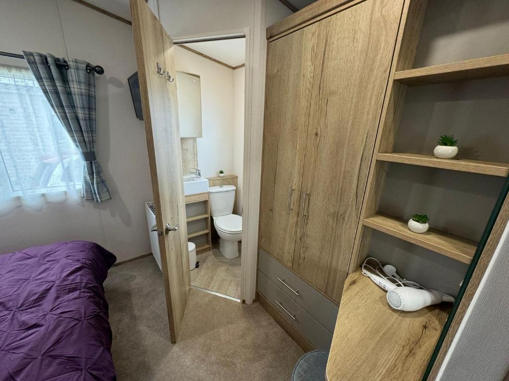 a small bathroom with a bed and a toilet at Golden Palm Resort - The Blenheim Retreat - Coastal Caravan Breaks in Chapel Saint Leonards