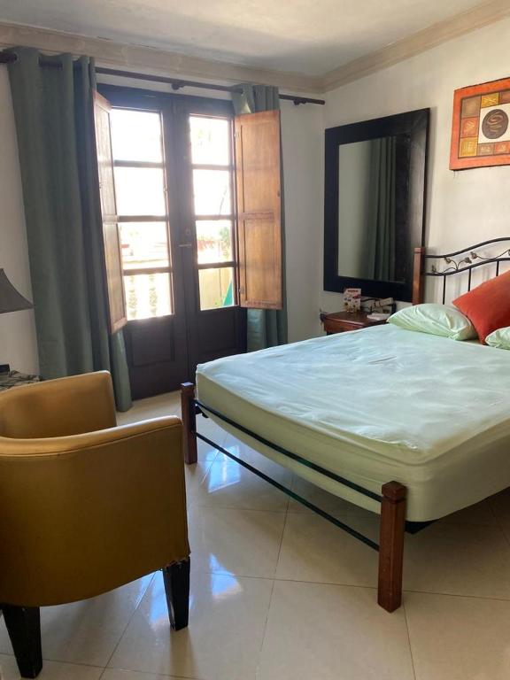 Un dormitorio con una cama y una silla y ventanas. en Colonial zone great location private room, en Santo Domingo