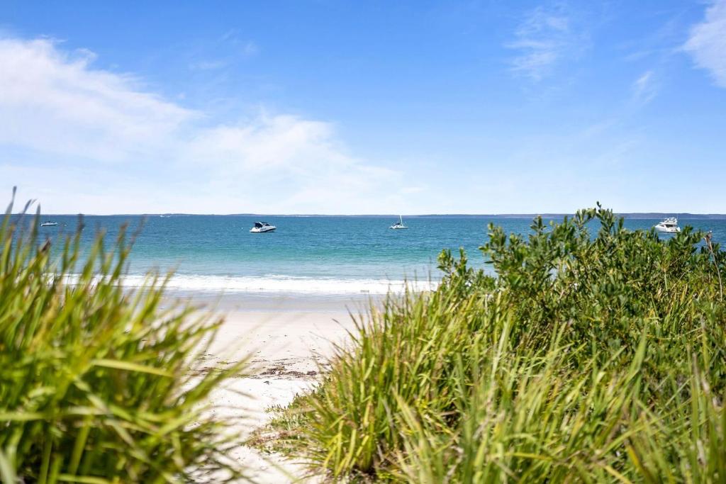 ein Strand mit Booten im Wasser und etwas Gras in der Unterkunft Sabia Beach House Vincentia - Family Fun - Beachfront in Vincentia