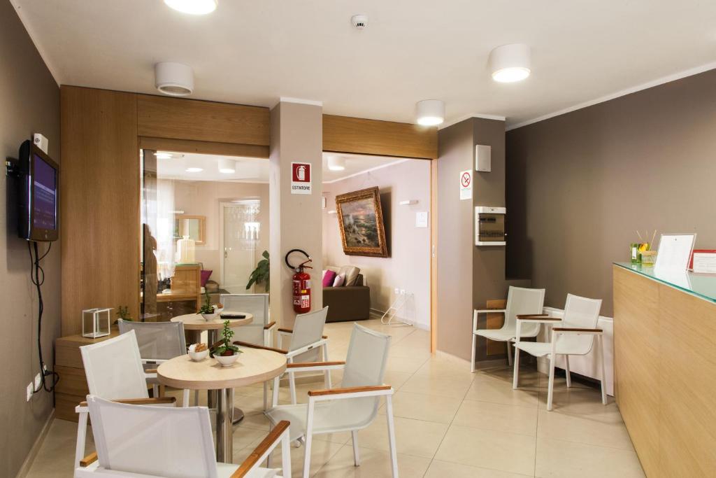 a restaurant with white chairs and tables and a kitchen at Alma di Alghero Hotel in Alghero