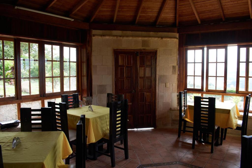 a dining room with two tables and chairs and windows at Eco Lodge Los de Arriba en Lago Calima para dos personas in Restrepo
