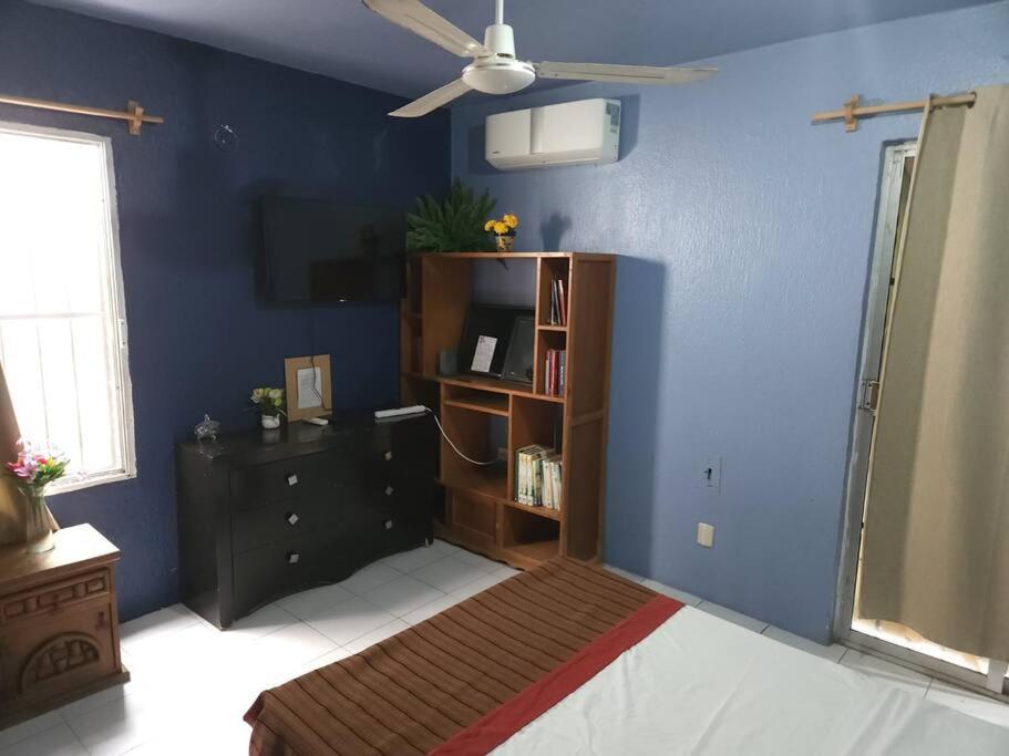 ein blaues Zimmer mit einem Bett und einem Bücherregal in der Unterkunft Departamento en el corazón de cozumel in Cozumel