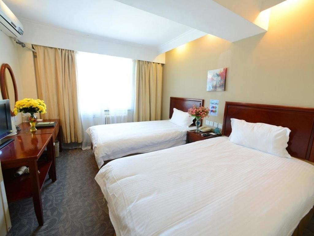 a hotel room with two beds and a television at GreenTree Inn ShanDong YanTai FuShan District YongDa Street Express Hotel in Yantai
