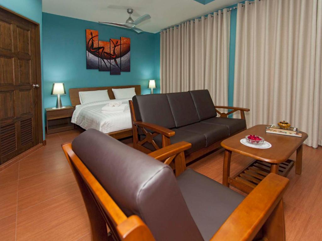 a hotel room with a bed and a couch and a table at Pattaya Garden Apartments Boutique Hotel in Pattaya South