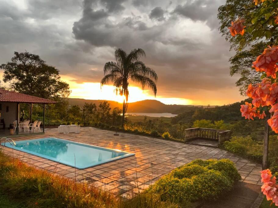 a swimming pool with a sunset in the background at Recanto do Coração in Itaúna