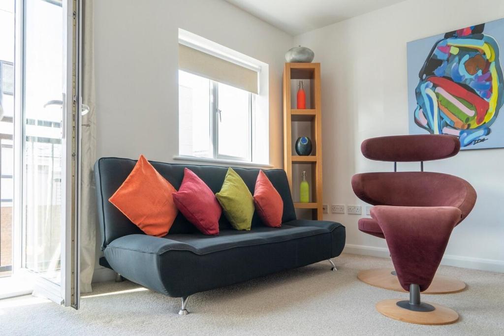 a living room with a blue couch with colorful pillows at 2 Bed Charming Duplex in Kidlington