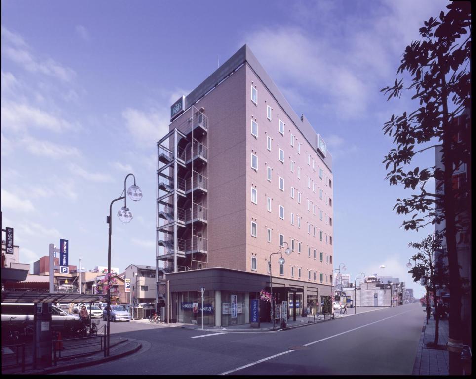 Un edificio alto en una calle de la ciudad con una farola. en Washington R&amp;B Hotel Kumagaya Ekimae, en Kumagaya