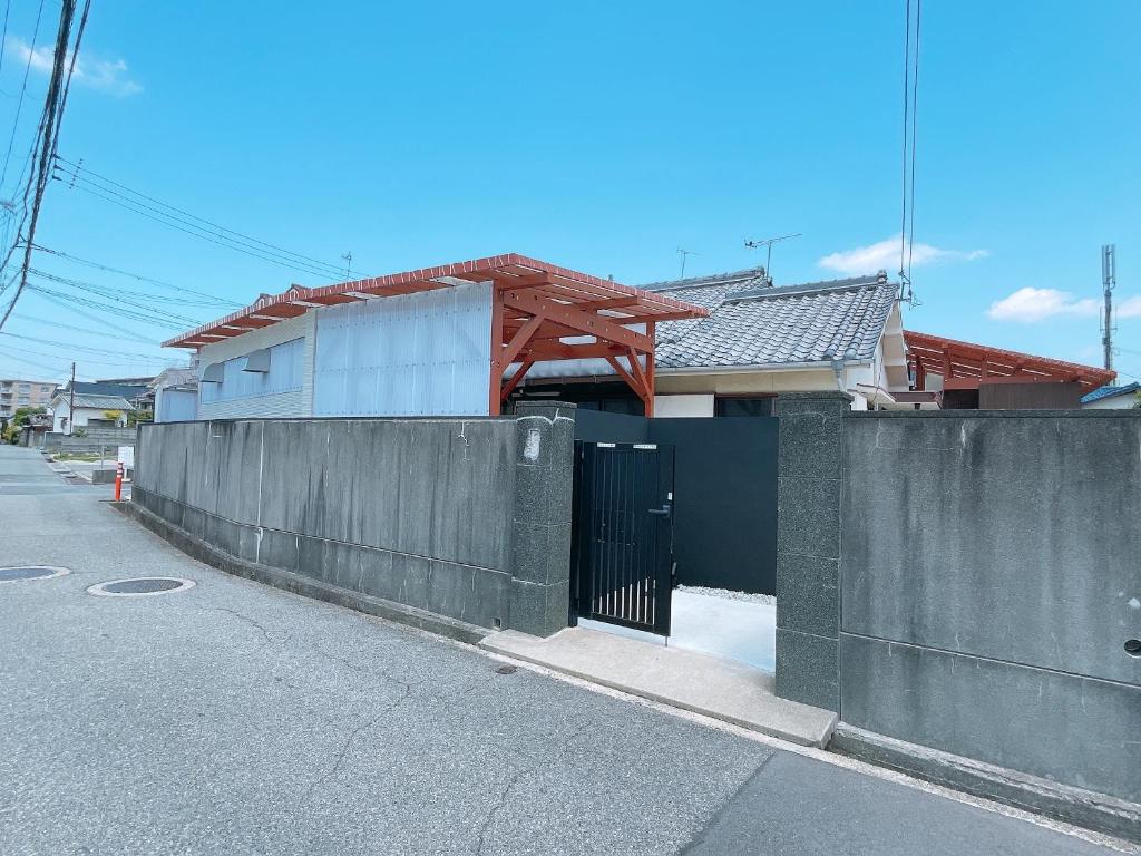 a fence in front of a house on a street at 淡路島一望 海まで1分 本格檜サウナのある古民家 10人まで定額料金 in Akashi