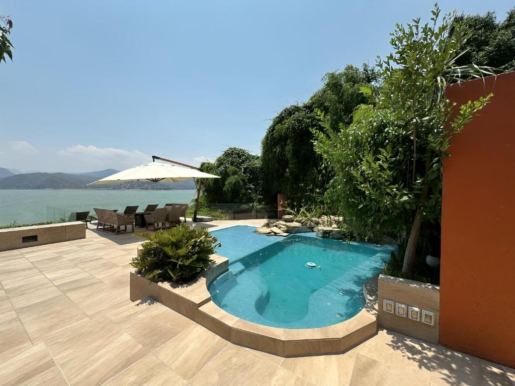 a swimming pool next to a patio with an umbrella at Casa el mirador-Valle de Bravo in Colorines