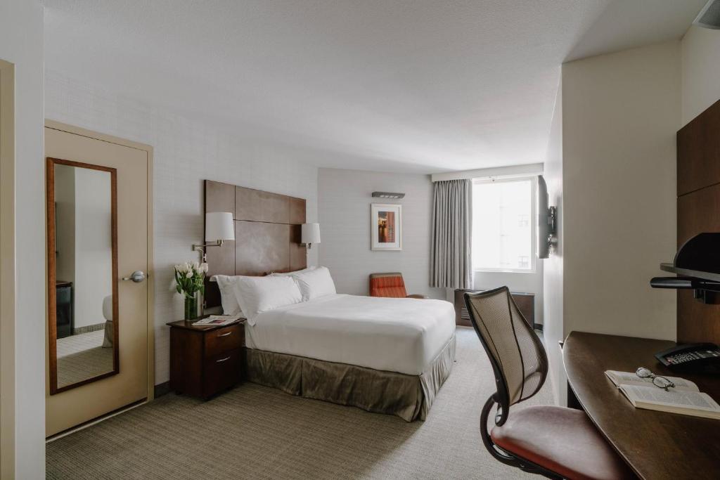 a hotel room with a bed and a mirror at Club Quarters Hotel Embarcadero, San Francisco in San Francisco