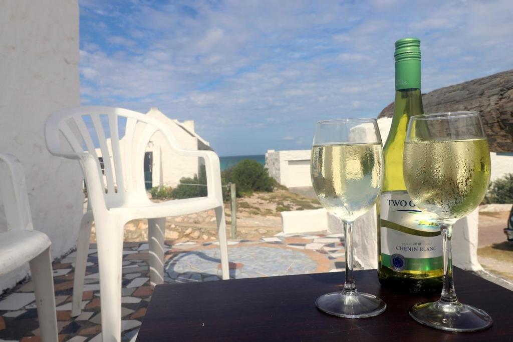 a bottle of wine and two glasses on a table at Dyers House Kassiesbaai Arniston in Arniston