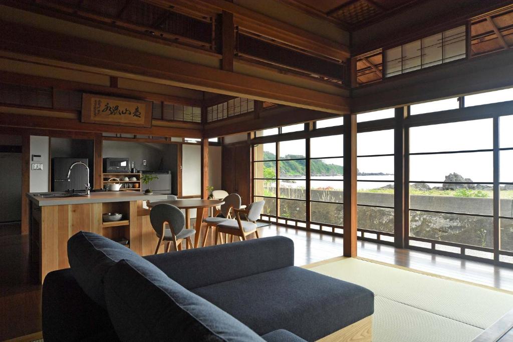 a living room with a couch and a kitchen with windows at お宿 山本 in Iwadate