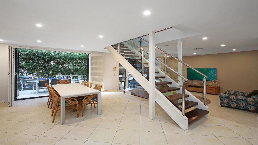 a living room with a staircase and a table and chairs at Alemar Close To Beach, Shops and Cafes Accom Holidays in Avoca Beach