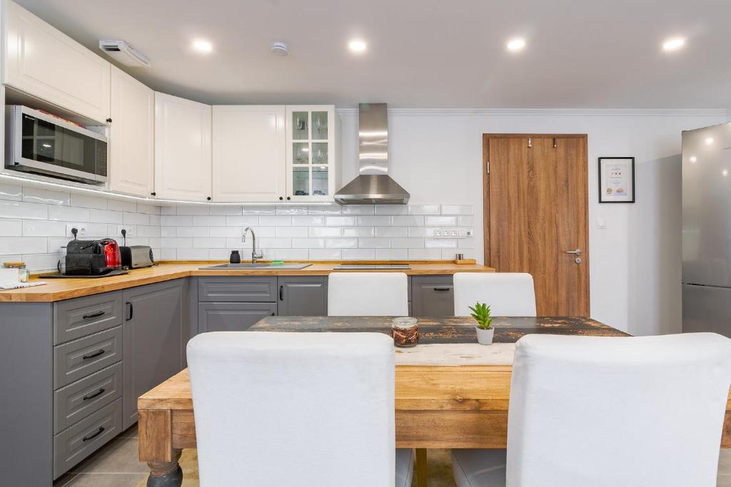 a kitchen with a wooden table and white cabinets at Monbuhim Premier in Veszprém