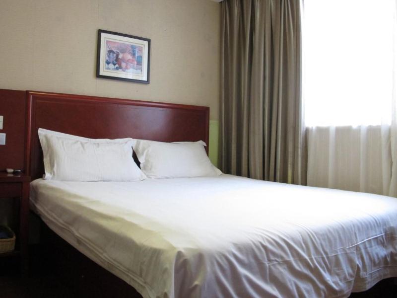 a bed in a hotel room with a large window at GreenTree Inn Zhejiang Zhoushan Xincheng Business Hotel in Zhoushan