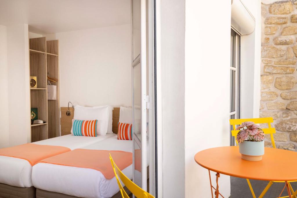 a small room with a bed and a table at Grand Hotel Du Calvados in Paris