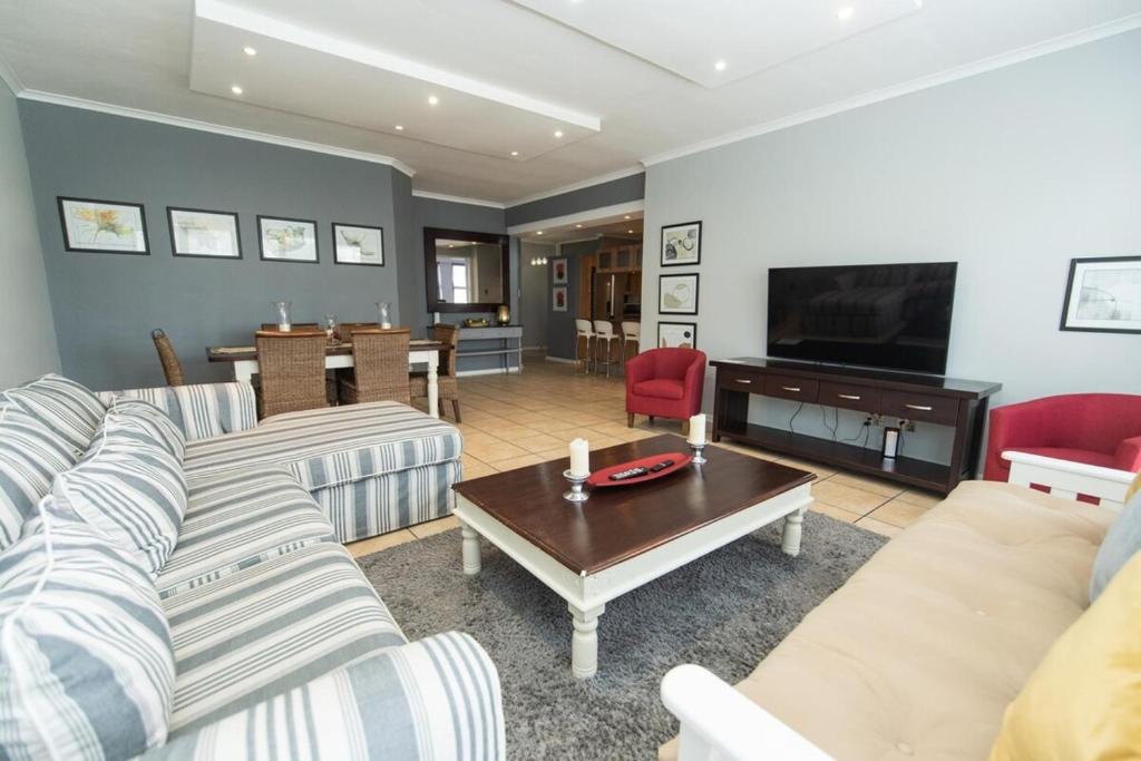 a living room with couches and a television and a table at Endless Summer Coastal Condo in Summerstrand