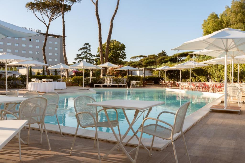 una piscina con tavoli, sedie e ombrelloni di Hotel Cristoforo Colombo a Roma