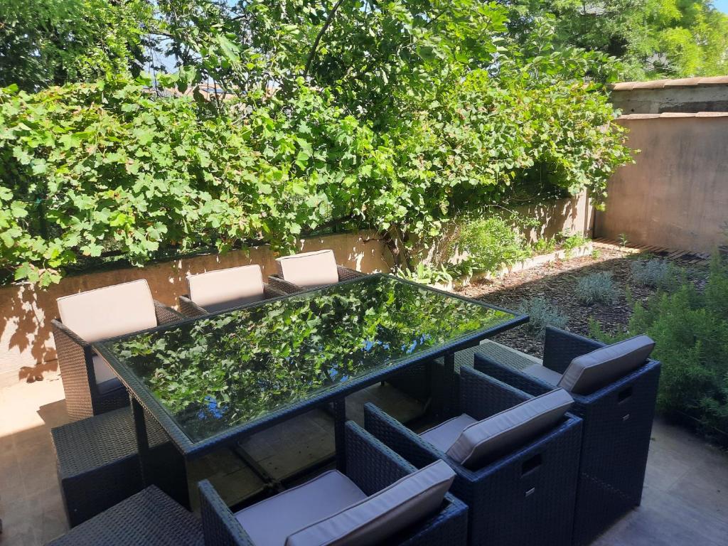 une table et des chaises en verre dans l'arrière-cour dans l'établissement Maison l isle sur la sorgue, à LʼIsle-sur-la-Sorgue