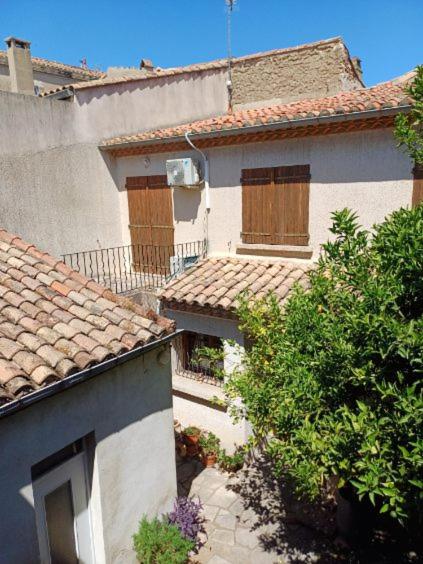 Elle offre une vue sur l'extérieur d'une maison blanche dotée de fenêtres. dans l'établissement L hacienda de Raymonde, à Nîmes
