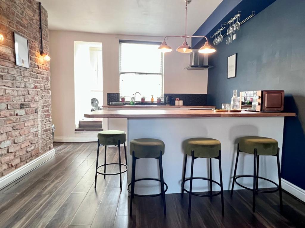 a kitchen with three bar stools at a counter at Ropewalks City Centre Apartment with Roof Terrace in Liverpool