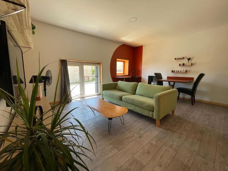 un soggiorno con un divano verde e un tavolo di Appartement neuf au coeur du vignoble dans village tous commerces a Cahuzac-sur-Vère