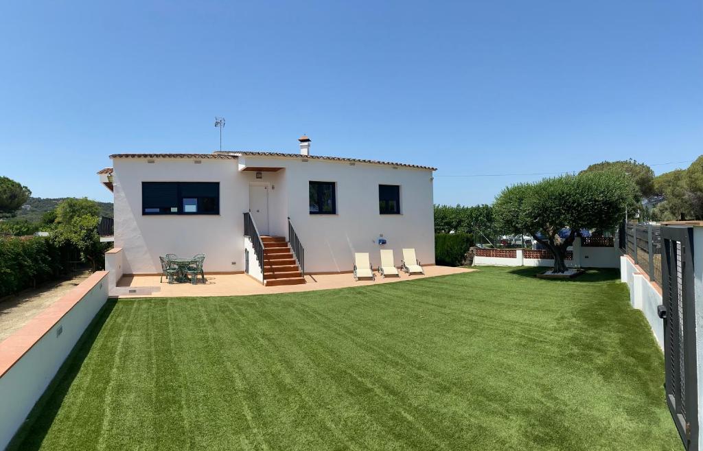 une maison avec une grande cour avec de l'herbe verte dans l'établissement Mas Tauler, à Sant Antoni de Calonge